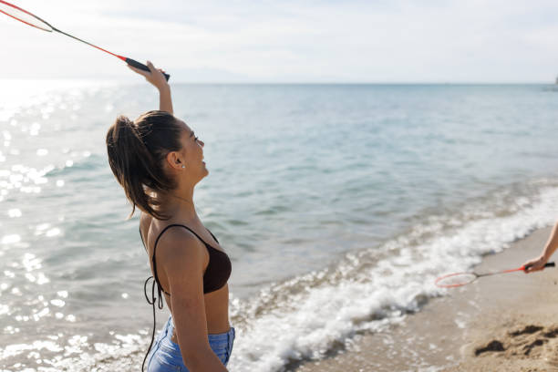 Young woman having fun while playing badminton on the beach
