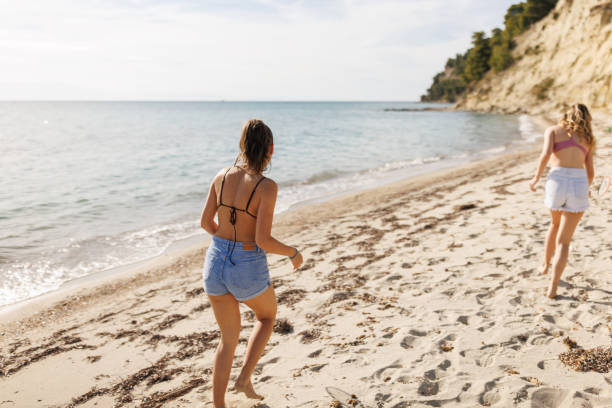 istock Cheerful young female friends having fun while playing badminton on the beach 2169155118