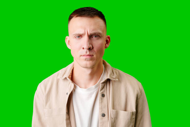 istock Young Man Posing With Serious Expression Against Bright Green Background 2169173548