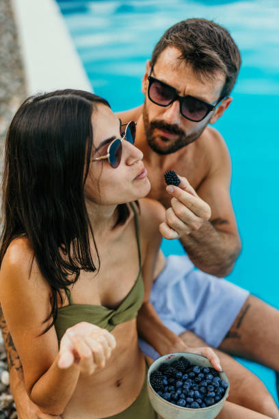 istock Attractive couple having a snack by the pool 2169176060