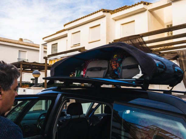 Father of a family who has finished loading all the suitcases on the luggage rack. Now all that's left to do is to close the luggage and start the trip.