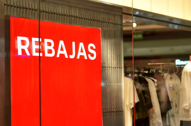A red sign with the word Rebajas written on it. The sign is hanging in a store window