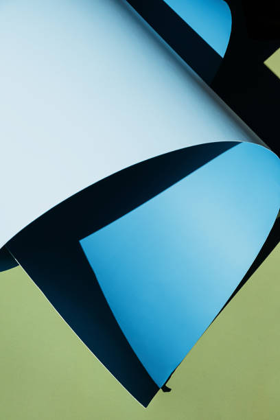 istock Curled blue paper creating shadows on green background. 2169183562