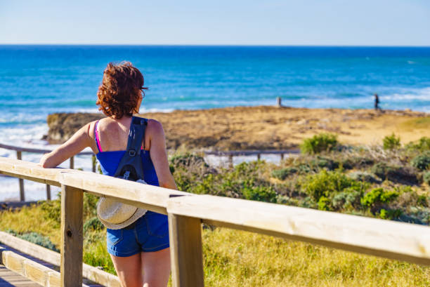 istock Woman walking on wooden path on sea shore 2169191264