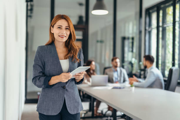 istock Professional woman smiling and using tablet in modern office setting. 2169192309