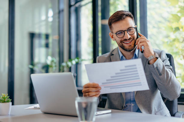istock Focused professional man smiling while talking on smartphone in bright modern office 2169192504