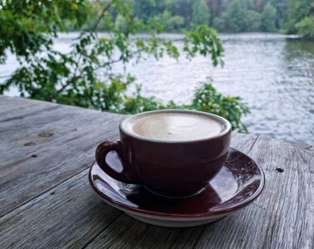 Coffee cup on a wooden platform next to a lake between mountains