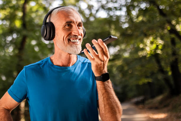 istock Mature Man with Headphones Checking Smartphone at Park 2169195014