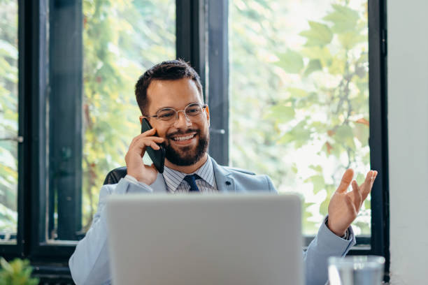 istock Businessman working on laptop and talking on cellphone 2169195159