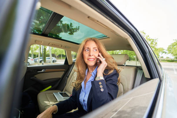 istock A woman is talking on her cell phone while sitting in a car 2169195771