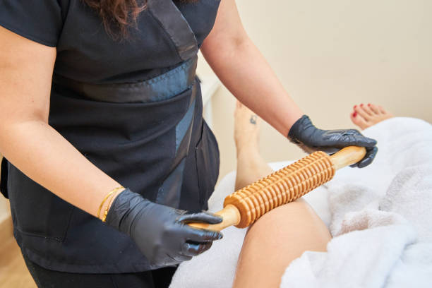 istock Masseuse Massaging leg With Wood Massage Roller Crop anonymous masseuse massaging female clients leg with wooden massage roller during rehabilitation session in spa salon 2169196202
