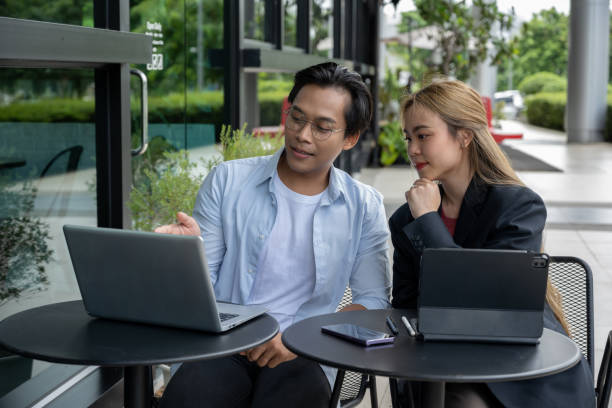 istock Two businessmen discussing work using tablets and laptops in a modern coffee shop. 2169198866