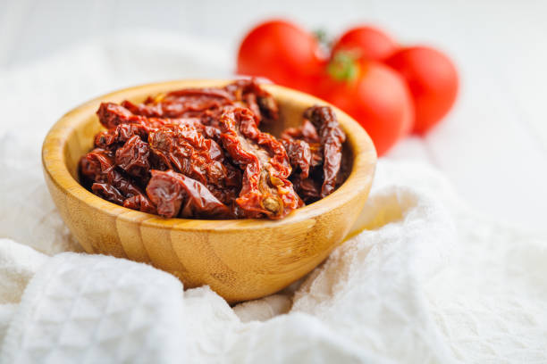 Sun dried red tomatoes in bowl on a white table.