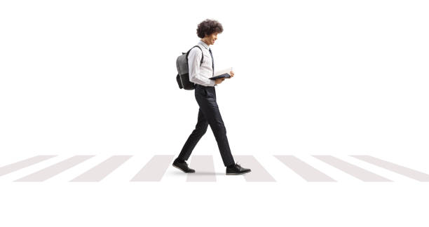 istock College student reading a book and walking at a pedestrian crossing 2169201664