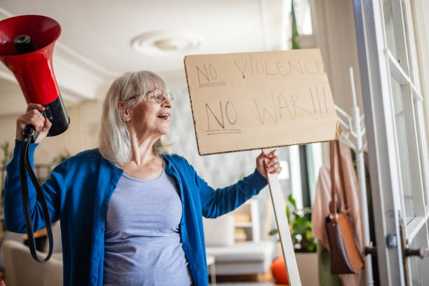 istock Activist holds a megaphone and a protest sign indoors. 2169207520