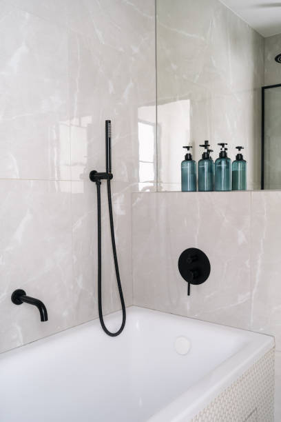 istock Modern bathroom featuring a sleek bathtub with a handheld shower and decorative bottles of bath products on display 2169210862