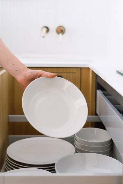 istock A person organizing white dinner plates in a modern kitchen drawer 2169210913