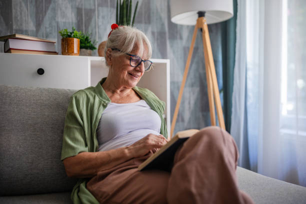 istock Elderly woman immersed in a book while sitting comfortably. 2169211101