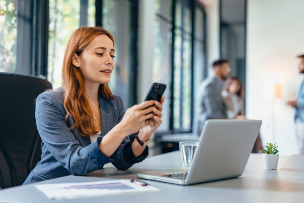 Professional woman with smartphone working in modern office setting