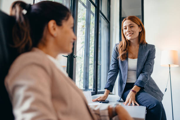 istock Two attractive businesswomen sit at desk discuss project 2169212108