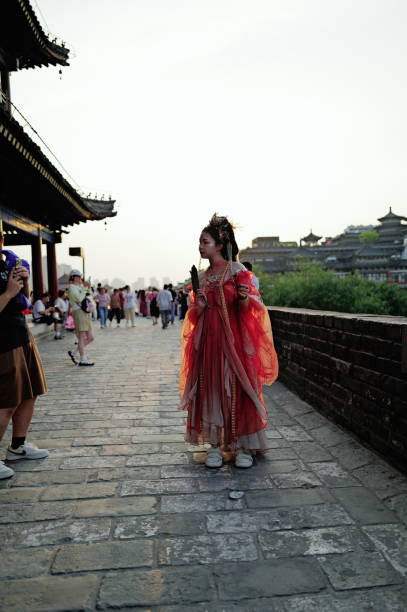 Xi’an China - August 24 2024: A large number of tourists gather on Xi'an's Yongning Gate City Wall to sightsee and take photos. Some visitors are dressed in traditional Hanfu, blending into the historical ambiance of the ancient city wall. They stroll along the wall, capturing memories that combine ancient and modern experiences. The city wall is lively, showcasing the fusion of history and culture.Captured with the Leica Q3.Thailand.