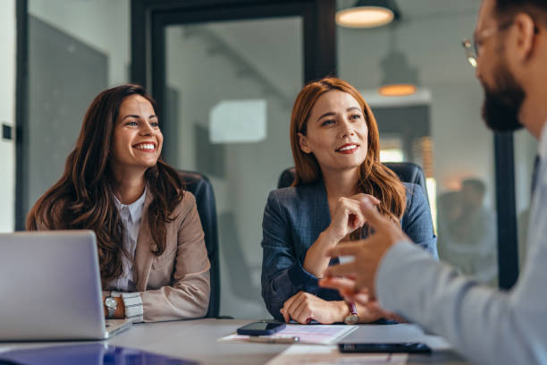 istock Three professionals in meeting sharing ideas around table 2169214997