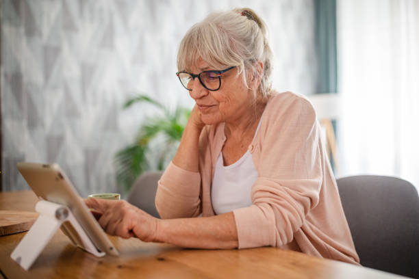 istock Senior woman using tablet with kickstand at wooden table 2169215936