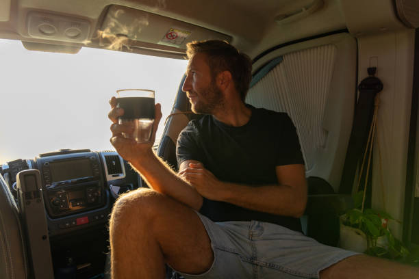 istock Man Relaxing with Hot Drink Inside a Camper Van 2169219023