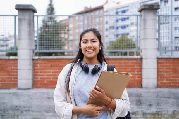 istock Latin student happily posing with books at university campus 2169219454
