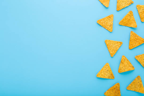 istock Yellow tortilla chips on light blue table background. Pastel color. Closeup. Empty place for text. Top down view. 2169220281