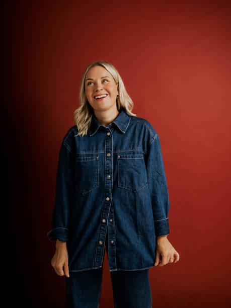 istock Woman in denim jacket and pants on red background in studio 2169222037
