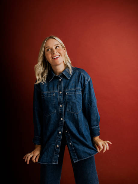 istock Woman in denim jacket and pants on red background in studio 2169222130