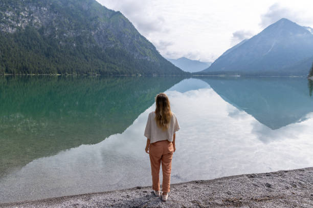 istock Woman Admiring Mountain Reflections by a Tranquil Lake 2169222134