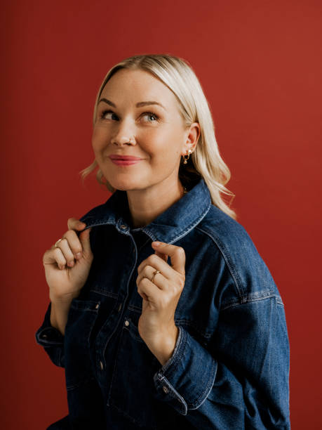 Woman in denim jacket and pants on red background in studio