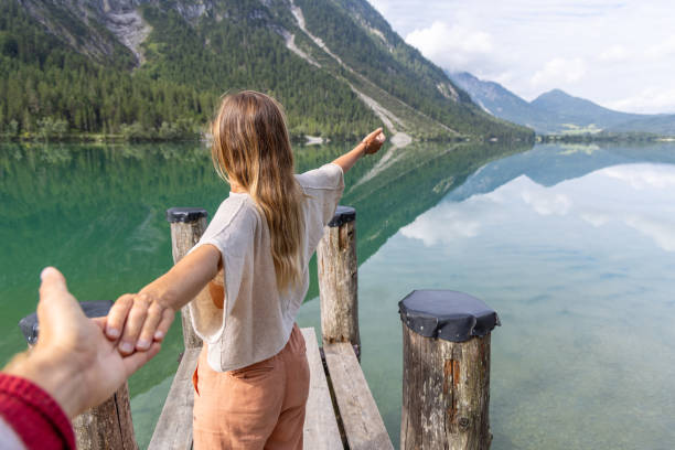 istock Couple Holding Hands on a Scenic Lake Pier 2169222344