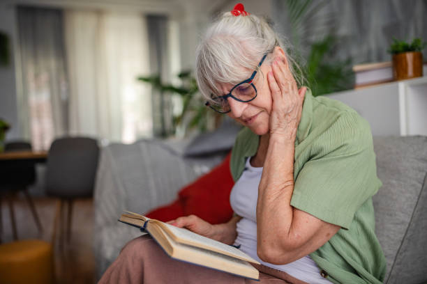 istock Senior woman engaged in reading on comfortable sofa. 2169222472