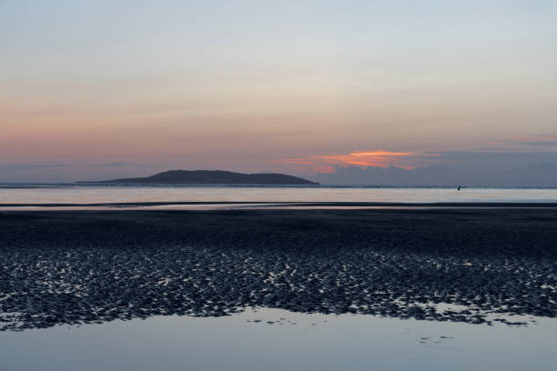 An early morning view from Malahide Beach as the tide goes out and the sun rises with Irelands Eye in the distance