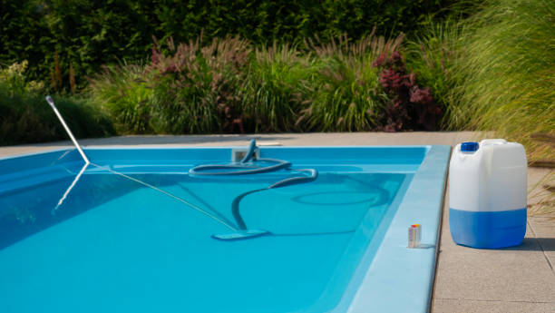 istock Pool cleaning hose and vacuum head with a large chemical container and water testing kit on the poolside, emphasizing water sanitation and maintenance. 2169226446