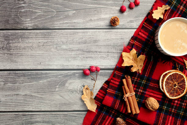 istock Autumn flat lay composition. Top view red plaid with coffee cup, cinnamon sticks, red berries, fall leaves, oranges on wooden desk table. 2169226873