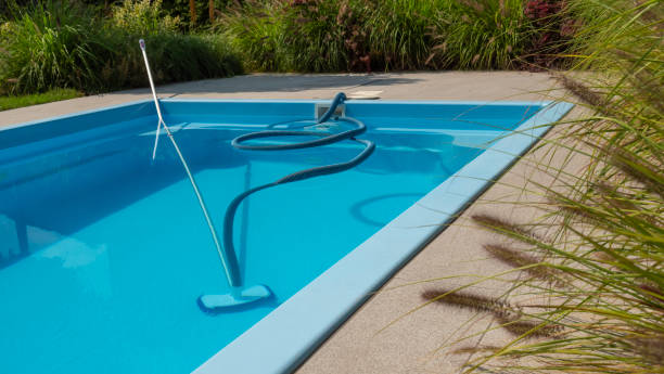istock A pool cleaning hose and vacuum head in a clear blue pool, surrounded by greenery, emphasizing maintenance and cleanliness. 2169226888