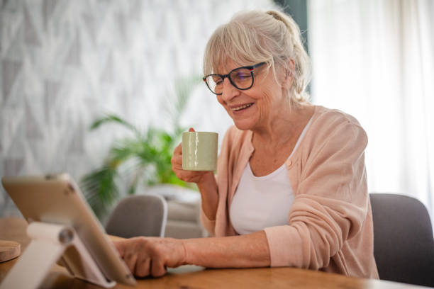 istock Elderly woman smiling and drinking coffee using tablet 2169227092