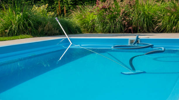 istock A pool cleaning hose and skimmer in a clear blue pool, surrounded by lush greenery, emphasizing pool maintenance. 2169227324