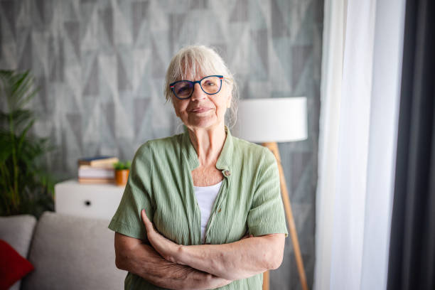 istock Elderly woman standing with arms crossed, looking content. 2169227476