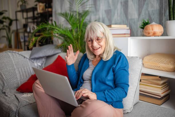 istock Elderly woman waving while using a laptop. 2169228085