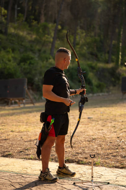 istock A man is holding a bow and arrow in a field 2169229253