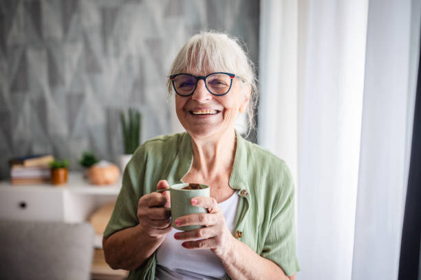 istock Happy elderly woman holding cup, smiling joyfully. 2169230372