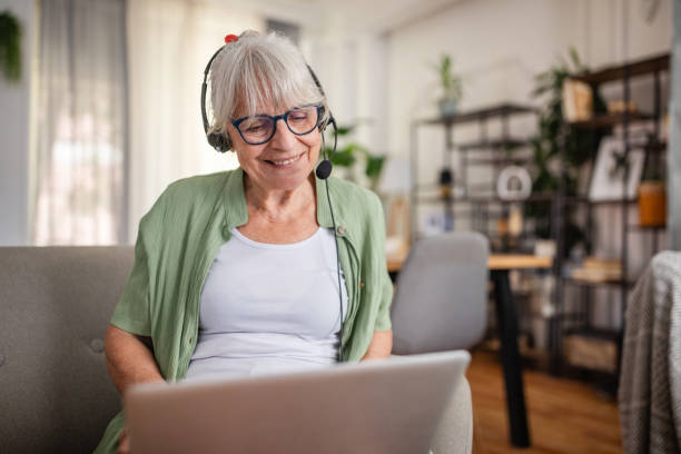 istock Happy elderly woman on video call wearing a headset 2169230430