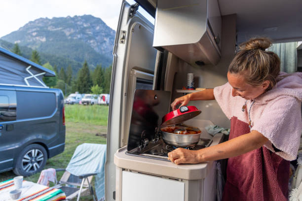 istock Woman Cooking in Camper Van Kitchen at Mountain Campsite 2169238149