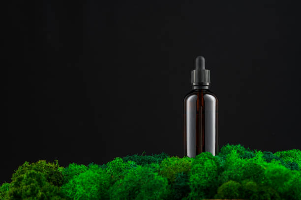 istock Dark glass dropper bottle on vibrant green moss against a black background 2169238152