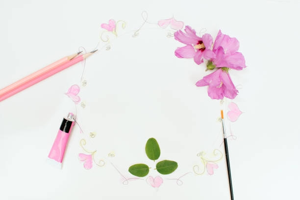 Circular frame drawn with pencil, painted with watercolors, brush, pencils, a tube of paint, romantic love and floral elements, creative copy space.